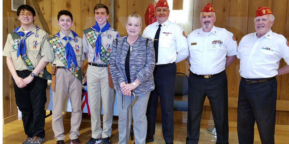 A detachment member in a scarlet shirt and red cover at a community gathering